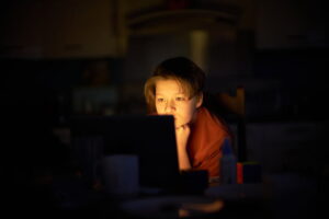 A Teenage Boy Sitting At The Dinning Table In The Dark
